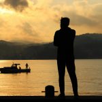 free photo of man standing near water at sunset