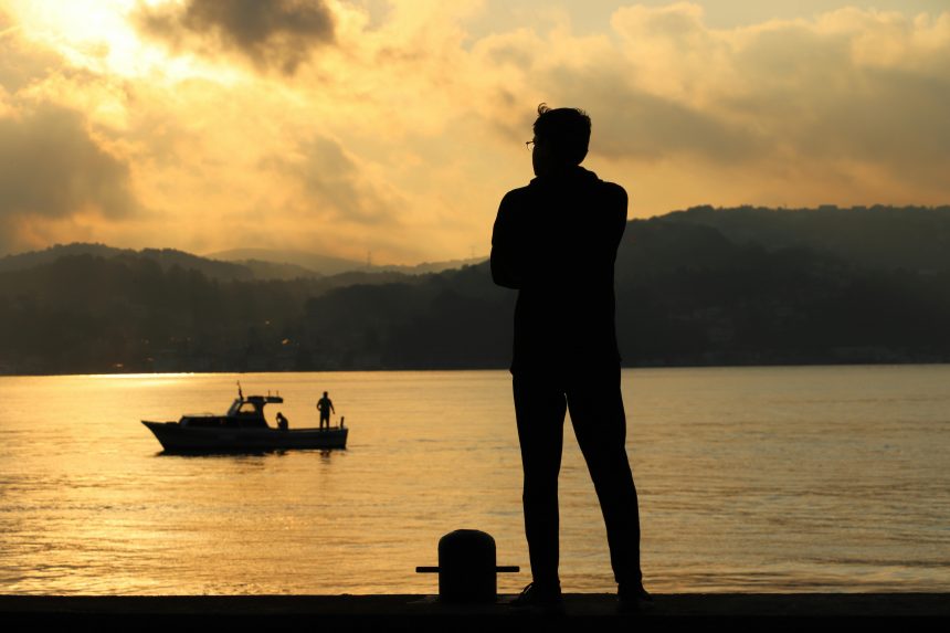 free photo of man standing near water at sunset